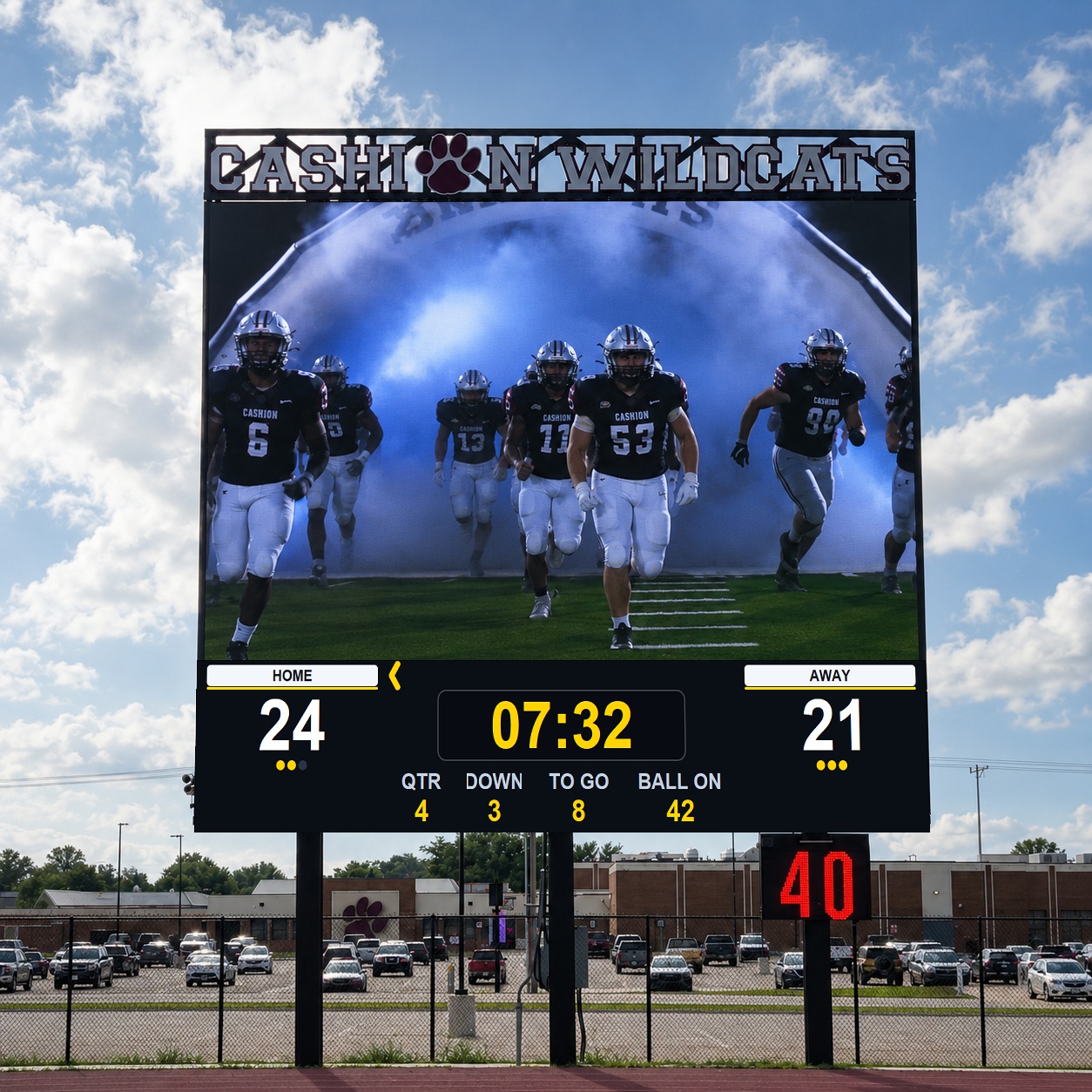 A Microframe Videoboard and Omniboard installed at a high-school football stadium — marquee on top, the videoboard running the team intro, and the Omniboard scoreboard below